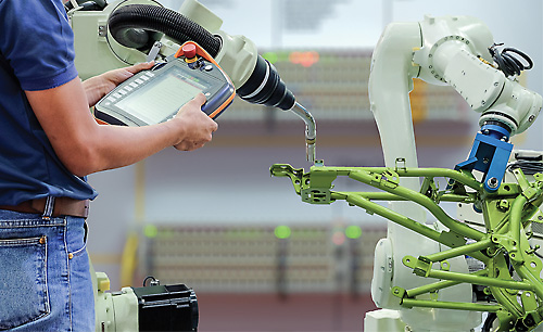 Engineers use a wireless remote control of robotic welding and robot workpiece for smart factory, industry 4.0 concept